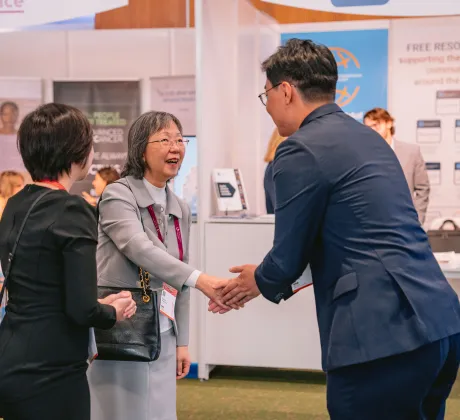 Anne Lee shaking hands with a participant at the 2024 World Cancer Congress