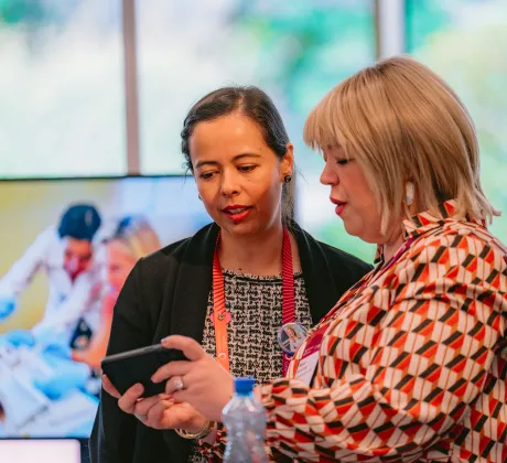 Two participants at the 2024 Congress in discussion look at a mobile phone