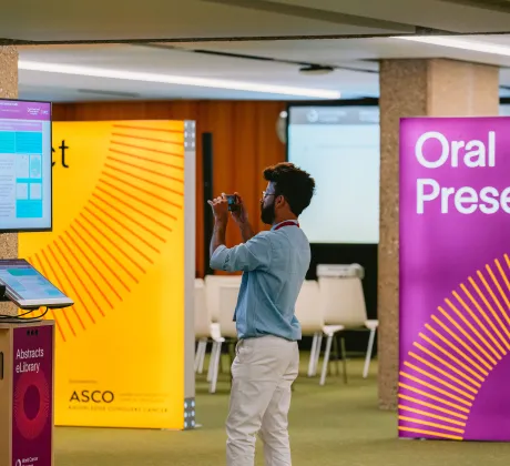A participant takes a picture of an abstract at the 2024 World Cancer Congress