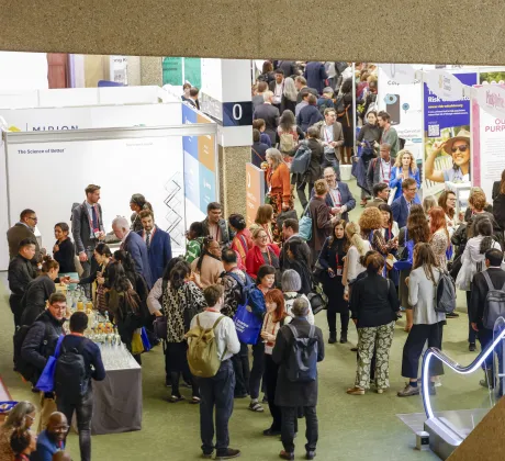 Participants gather and network in the Global Village exhibition area at the World Cancer Congress 2024 in Geneva, surrounded by branded booths, presentation spaces, and catering stations.