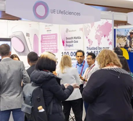 World Cancer Congress 2024 participants stand in conversation at an exhibition booth, with branded displays and informational panels visible in the background.