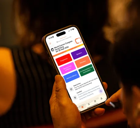 A person holding a phone showing the UICC Events app
