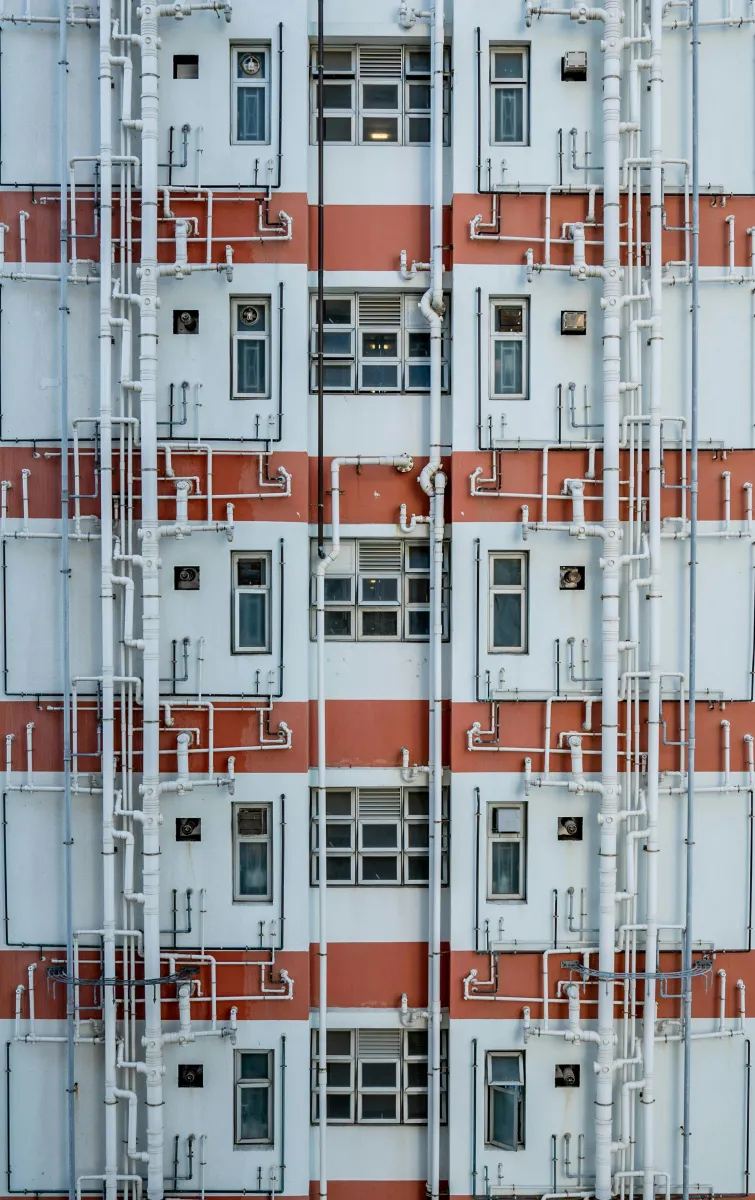 The facade of a residential building with pipes snaking around the windows